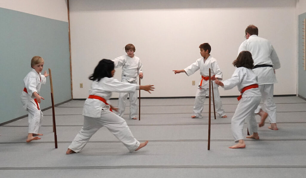 Students stand in a circle holding wooden swords